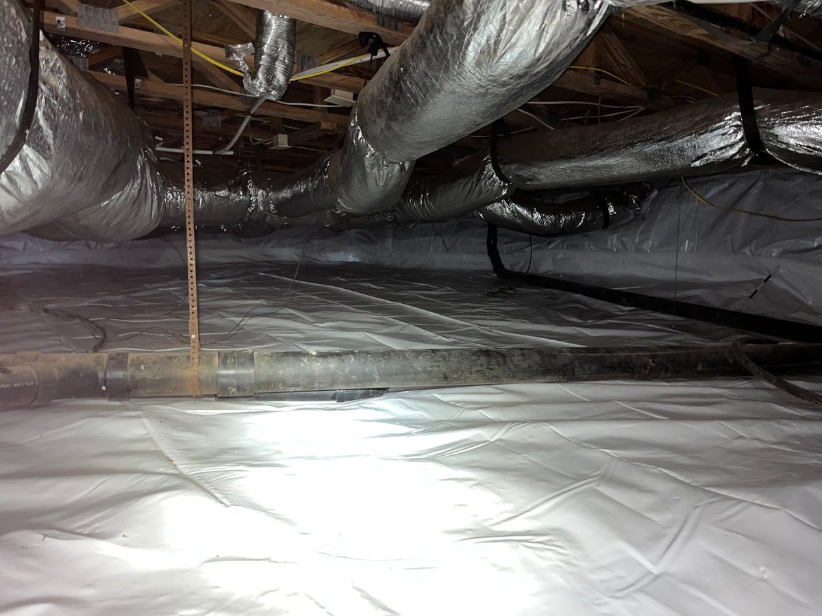 Crawlspace with white vapor barrier and insulated ductwork wrapped in foil and plastic